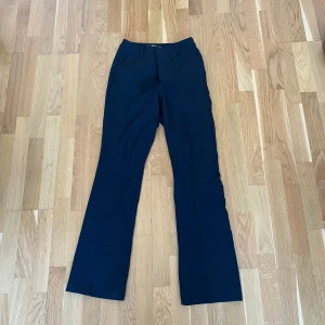  Bikbok Svarta kostymbyxor med bootcut - Snygga svarta kostymbyxor med klassisk bootcut-passform. Byxorna har normal midja och stängs med dragkedja och knapp framtill. Perfekta för en stilren look och passar till många olika outfits.