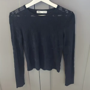 Blå  långärmad topp från Zara - Säljer en blå långärmad topp från Zara i storlek M. Toppen har ett diskret blommigt mönster i tyget och är tillverkad i ett tunt, lätt material. Perfekt att styla med jeans eller kjol för en snygg look.