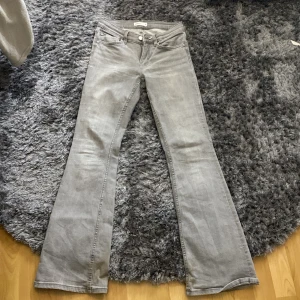 Ljusgrå bootcut jeans från Gina tricot  - Säljer ett par ljusgrå jeans från Perfect Jeans med bootcut-passform. Jeansen har klassisk femficksdesign, normalhög midja och stängs med dragkedja och knapp. 