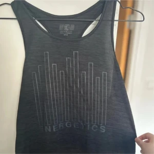 Svart träningslinne - Snygg grå linnetopp med ett coolt tryck på framsidan. Perfekt för träning eller en avslappnad dag!💕