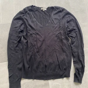 Svart v-ringad tröja - En enkel svart v-ringad tröja med långa ärmar. Perfekt att matcha med jeans eller kjol. Tröjan är tunn och har en klassisk passform med ribbade muddar vid ärmslut och nederkant.