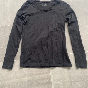 Svart långärmad basic tröja - En enkel svart långärmad tröja från Basic Girl. Perfekt att ha som basplagg och funkar till det mesta. Mjuk och skön bomullskänsla med rund halsringning.