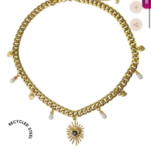 Guldfärgat halsband med pärlor och hjärthänge - Säljer ett chunky guldfärgat halsband med kedja i återvunnet stål. Halsbandet har små pärldetaljer och ett solformat hänge med hjärta i mitten. Perfekt statement-accessoar! Jätte fint använt en gång så i helt nytt skick💕