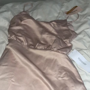 Dusty pink satinklänning från Bubbleroom - Supersöt maxi klänning i dusty pink från Bubbleroom. Gjord i glansigt satinliknande material med smala axelband och öppen rygg.