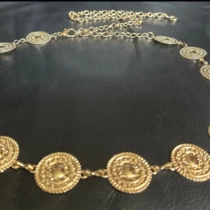 Concho Belt / Kedjebälte i guldfärgad metall – western, boho & festivalstil - Dekorativt conchobälte i guldfärgad metall med vintagekänsla – ett riktigt statement för dig som gillar boho, western eller festivalstil. Justerbar längd gör att det kan bäras i midjan, på höften eller över klänning. Metallplattorna har en detaljerad, snäckformad design med inspiration från traditionellt hantverk. Längd ca 63–115 cm, plattor ca 2,7 cm. Skick: Ny/oanvänd. Ingen prutning – men jag ger bundlerabatt. Kika gärna på mina andra annonser! 