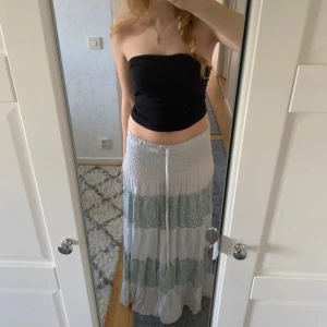 Lång kjol med blommigt mönster och snörning - Säljer denna fina långkjolen i vit med blommiga partier i grönt och blått💕Går även att bäras som en klänning, se tredje bilden.  Köpt på en marknad i Egypten. Mycket fint skick förutom några lösa trådar och en söm på sidan. Jag bär S men den är väldigt stretchig så passar fler storlekar. Så skön och luftig!