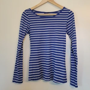Blåvit randig långärmad tröja - Liten i storlek. Snygg långärmad tröja med blå och vita ränder. Figurnära modell. 