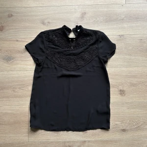 fin svart blus med spets runt halsen - en väldig fin skön blus med fina detaljer. 