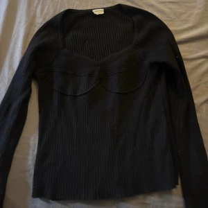 Svart ribbad långärmad tröja - Svart ribbad långärmad tröja från Gina Tricot med snygg v-ringad halsringning och dekorativ söm över bysten. Stretchigt material som sitter skönt och markerar figuren. Perfekt till jeans eller kjol för en stilren look.