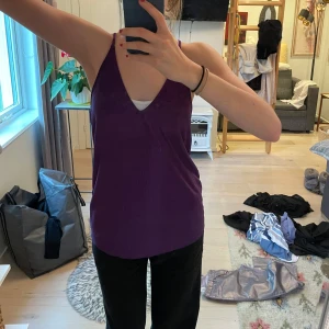 Lila linnetopp från Zara - Säljer en snygg lila linnetopp från Zara med smala axelband och v-ringning. Toppen har en lätt ribbad struktur och är i ett tunt, flowy material som känns skönt mot huden. 