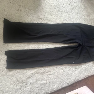 Svarta kostymbyxor från Nelly - Svarta kostymbyxor från Nelly i klassisk rak modell. Byxorna har en låg midja och är i ny skick! Är 165cm låg och dom passar perfekt till mig, skriv vid intresse eller fumderingar!❤️