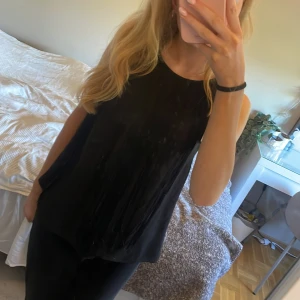 Svart fransig linnetopp från Lindex XS - Svart ärmlös linnetopp från Lindex i storlek XS. Toppen har långa fransar framtill som ger en cool och trendig look. Baksidan är lätt transparent med knapp i nacken. Perfekt att styla med jeans eller kjol för en snygg outfit.