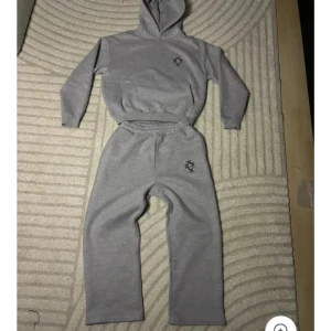 Grå mjukisbyxor med broderad logga - Grå mjukisbyxor med elastisk midja och rak passform. Byxorna har en broderad logga framtill på benet och är tillverkade i mjukt bomullsmaterial. Perfekta för en chill och avslappnad stil.har alla storlekar