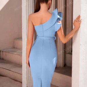 Ljusblå one shoulder klänning med volang - Superfin ljusblå klänning med en axel och volangdetalj. Sitter figurnära med bälte i midjan och slits bak. Perfekt för dig som vill sticka ut med en elegant och modern look. Materialet känns mjukt och följsamt.