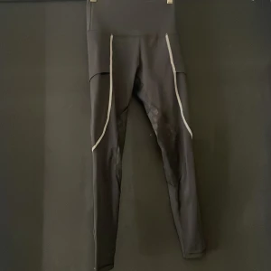 Svarta Maya Delorez byxor - Svarta ridbyxor från Maya Delorez med en ficka för telefonen och har en tight passform och stretchigt syntetmaterial som ger bra rörelsefrihet. Guldig logga på sida och diskret logga där bak. Byxorna är i bra skick. XXS/XS