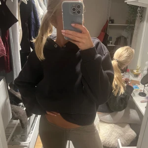 Svart hoodie med huva från bik bok - Svart oversized hoodie med huva och stor ficka framtill. Tröjan har långa ärmar och en klassisk, enkel design utan tryck eller mönster. Perfekt för en chill och avslappnad stil. Mjuk och skön, passar till allt.