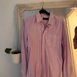 Rosa- och vitrandig skjorta från H&M - Säljer en långärmad skjorta från H&M med rosa och vita vertikala ränder formade som blommor typ.