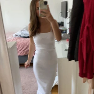 Vit långklänning från Gina Tricot - Säljer en stilren vit långklänning från Gina Tricot. Klänningen är ärmlös med smala axelband och har en tight passform som framhäver figuren. Perfekt för sommarens alla tillfällen. Materialet är mjukt och stretchigt för extra komfort.