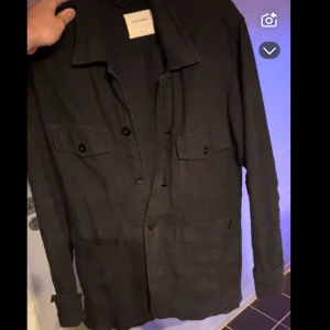 Svart overshirt från A Day's March - Säljer denna overshirt från A days march i använt skick men finns liv kvar i den . Finns defekt som ni kan se på bild ”2” 