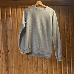 Grå sweatshirt från Pier One - En stilren grå sweatshirt från Pier One med klassisk rund halsringning och ribbade muddar. Tröjan är i mjuk bomullsblandning och har en relaxed passform som funkar perfekt till jeans eller joggers. Enkel och clean look som alltid är rätt.