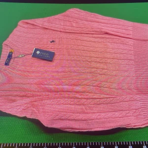 Rosa kabelstickad tröja Polo Ralph Lauren - Snygg rosa kabelstickad tröja från Polo Ralph Lauren med klassisk rund halsringning och broderad logga på bröstet. Tröjan har ribbade muddar och är perfekt för dig som gillar preppy stil. Materialet är mjukt och skönt, passar till många outfits.