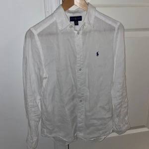 Ralph lauren linne skjorta  - Vit Ralph lauren linneskjorta - skick 9,5/10, mycket bra skick för utom en pytteliten fläck (bild 5). Dock inget som syns eller som man lägger märke till under användning! - storlek 14-16 år vilket motsvarar XS - sjukt snygg och eftertraktad till sommaren! - hör av er vid frågor🙌