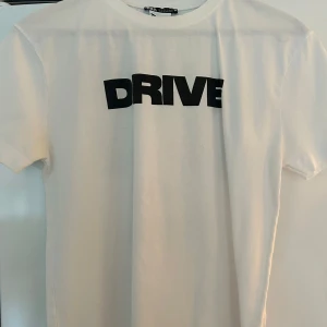 Vit t-shirt med Drive-tryck från Zara - Säljer en Vit t-shirt från Zara med svart texten 'DRIVE' på framsidan och ett stort tryck med motiv och texten 'ARE REAL Drive' på baksidan med Ryan gosling. Säljer pga av att den är för liten till mig.