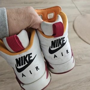 Nike Air Jordan 6 Retro 'Toro Bravo' - Säljer ett par Nike Air Jordan 6 Retro 'Toro Bravo' sneakers i vitt med röda och orange detaljer. Skorna har klassisk snörning, perforerade paneler och ikonisk Jumpman-logga på sidan. Perfekta för dig som gillar streetwear och vill sticka ut.