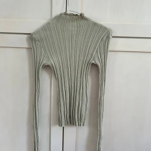 Grön ribbad polotröja från H&M - Säljer en grön ribbad polotröja från H&M. Tröjan har lång ärm, tight passform och hög hals. Materialet är mjukt och stretchigt och genomskinlig av sig, medvetet. 