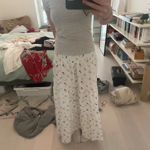 Vit långkjol med blommigt mönster - Säljer en vit långkjol med blommigt mönster. Har resår i midjan! Perfekt inför sommaren🫶🏻 Nypris 200kr 