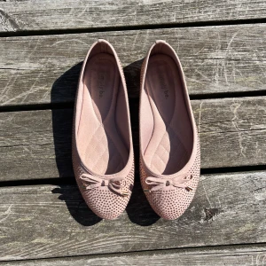 Ljusrosa ballerinaskor - Säljer ett par ljusrosa ballerinaskor med glittriga stenar och söt rosett framtill! Bra skick! Storlek 40-41