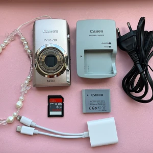 Canon IXUS 210 - Canon IXUS 210 är en stilren digitalkamera med 14,1 megapixlar och touchskärm. Perfekt för dig som vill ta snygga bilder på resor, fester eller vardagsäventyr. Paketet innehåller kamera, laddare, batteri, minneskort och smyckesrem.