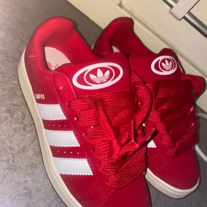Hell nya Röda Adidas Campus sneakers. Storlek 38 (priset kan diskuteras vid snabb affär) - Snygga röda Adidas Campus sneakers med vita detaljer. Perfekt för en avslappnad och trendig stil. Fick den som en present men tyvärr passade de inte mig. Oanvända men packet ingår ej. Storlek 38. Finns ingen återköp. Priset kan diskuteras vid snabb affär)