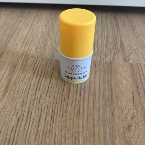 Drunk Elephant Lippe Balm - Läppbalsam från Drunk Elephant i en smidig vit och gul hylsa. Balsamet är i stiftform och har en krämig, ljusgul färg. Perfekt att ha med i väskan för återfuktade läppar hela dagen. Andvänd till lite mindre än hälften men skärde bort lite av det andvända så den är ren och oandvänd. 