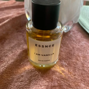 ESSNCE ..  I Am Vanilla .. Eau de Parfum - En stilren parfym från ESSNCE med doft av vanilj. Flaskan är rund och genomskinlig med svart lock och vit etikett. Innehållet är gyllengult och flaskan rymmer 50 ml. Se bilder hur mycket som är kvar.Perfekt för dig som älskar söta och varma dofter.
