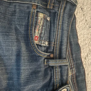 Blå bootcut jeans från Diesel - Säljer ett par klassiska blå jeans från Diesel med bootcut-passform. Jeansen har snygga slitningar, fem fickor och tydliga kontrastsömmar. Perfekta för dig som gillar en tidlös denimlook med lite vidare ben. Står att de är storlek 28 men passar mig som vanligtvis har s/xs i jeans!