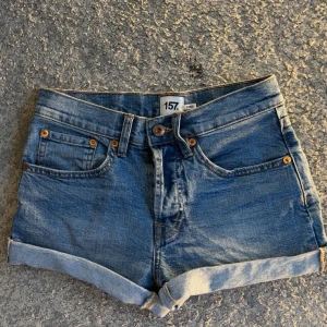 Blå jeansshorts från lager 157 - Säljer ett par klassiska blå jeansshorts från lager 157 Doris i storlek XS. De har upprullade benslut, fem fickor och synliga sömmar i kontrastfärg. Perfekta för varma dagar och enkel att matcha med olika toppar. Använda en gång när jag provade dom. Midjemåttet är 35 rakt över💕💕Dom är också medel waist💗