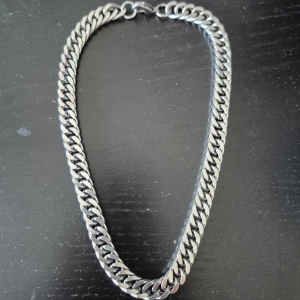 Stol silver halsband  - Stol halsband med breda, platta länkar i silverfärgad metall. Klassisk kedjedesign med karbinhake som lås. Perfekt för att ge en edgy touch till din outfit.