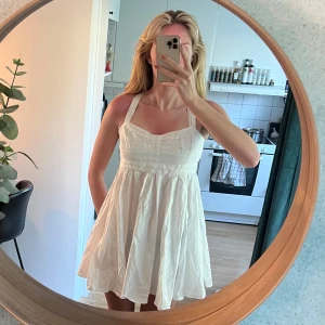 Vit kortklänning från Cubus - Säljer en söt vit kortklänning från Cubus med breda axelband som korsas i ryggen. Klänningen har en lätt utsvängd kjol och markerad midja, dragkedja baktill. Aldrig använd eftersom den är för liten för mig, jag har i vanliga fall S och denna kan jag inte knäppa i ryggen. 