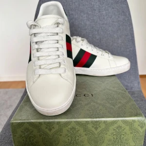 Gucci ace - Säljer ett par klassiska vita Gucci Ace sneakers  med de ikoniska gröna och röda ränderna på sidan. Perfekta för dig som gillar stilrena och lyxiga sneakers. Dem är i väldigt bra skick och bra pris. Men priset kan diskuteras vid snabb affär 