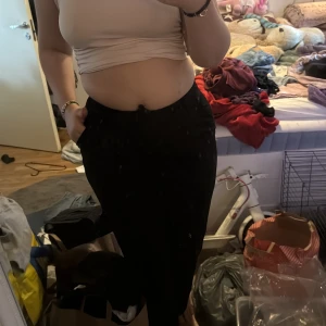 Svarta byxor från Divided H&M - Säljer ett par svarta byxor från Divided H&M med hög midja och lös passform. Byxorna har knapp och dragkedja framtill samt resår i midjan för extra komfort. Perfekta till många olika outfits.