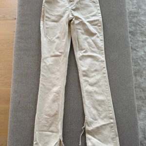 Beiga jeansbyxor från Zara - Säljer ett par jeansbyxor från Zara med raka ben och råa kanter nertill. Byxorna har klassisk femficksdesign och stängs med dragkedja och knapp. Perfekta till sommaren 
