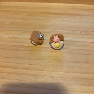 Söta örhängen med frukostmotiv - Unika örhängen formade som en brödskiva med stekt ägg och en rosa kanin. Färgerna är beige, vit, gul och rosa. Perfekta för dig som gillar lekfulla accessoarer med mattema.