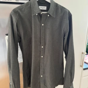 Mörkgrön skjorta från John Henric - Säljer en stilren mörkgrön tröja skjorta från John Henric med klassisk krage och vita knappar. Skjortan har lång ärm och är tillverkad i ett mjukt material som känns bekvämt mot huden. Perfekt för dig som gillar en enkel men snygg look.