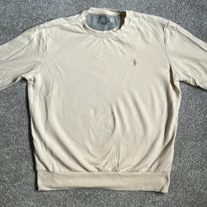 Beige sweatshirt från Polo Ralph Lauren - Säljer en stilren beige sweatshirt från Polo Ralph Lauren med rund halsringning och diskret broderad logga på bröstet. Tröjan är knappt använd (inte mer än max 5 gånger) och därför riktigt fräsch utan några defekter. Hör av dig om du har några frågor! Köparen står för frakt!