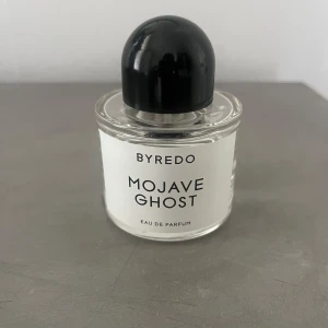 Byredo Mojave Ghost Eau de Parfum 50ml - Byredo Mojave Ghost Eau de Parfum i en stilren, rund glasflaska med svart rund kork.  50 ml och har en minimalistisk vit etikett med svart text. Parfymen är tillverkad i Frankrike och har en exklusiv känsla. Väldigt sparsamt använd 