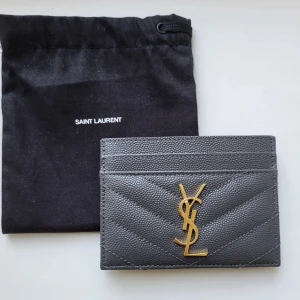 Grå plånbok från Saint Laurent - Hej, säljer min jättefina grå saint Laurent korthållare, som är i nästan helt nyskick och använts få gånger då jag fick fel färg i present! Har låda och äktenskapsbevis! Jättefin och passar till allt! Den har flera fack för kort och pengar🫶🏽🩵