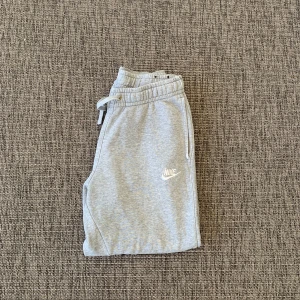 Grå mjukisbyxor från Nike - Snygga grå Nike mjukisbyxor som knappt är använda.  Byxorna har två sidofickor och en liten vit Nike-logga på vänster ben. Perfekta för chill eller träning. Storleken är m i barnstorlek och xs i mansstorlek.