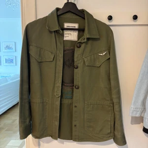 Zadig & Voltaire jacka - Säljer en olivgrön overshirt/jeansjacka från Zadig & Voltaire med broderad logga och tryck på ryggen. Jackan finns inte kvar på hemsidan. Pris kan diskuteras💞