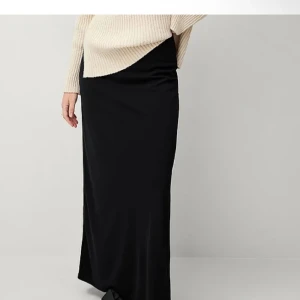 Svart långkjol med slits - Säljer en svart långkjol med slits på sidan. Kjolen har en rak och tight passform som sitter snyggt längs kroppen. Perfekt att styla med både sneakers och klackar. Enkel, vacker 